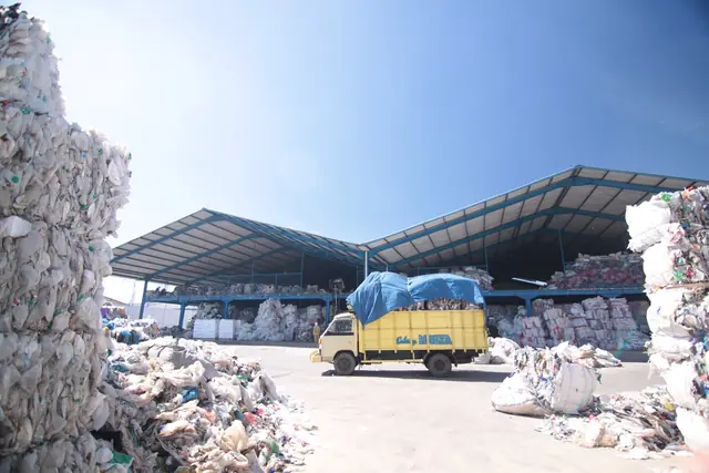 Truk di antara bal plastik bekas