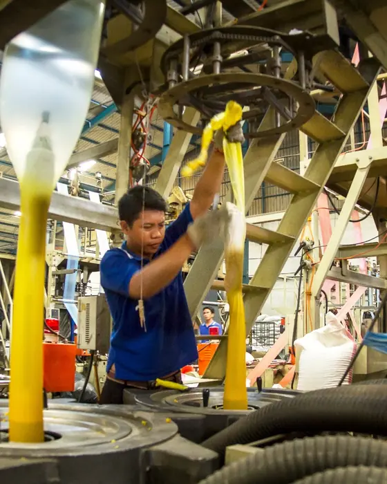 Operator mesin blown film dengan film berwarna kuning