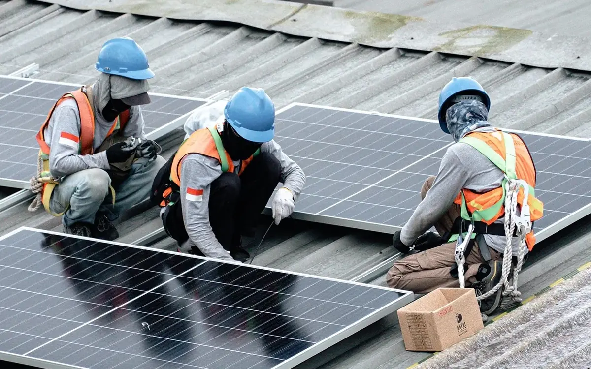 Technician inspecting the rooftop solar panels at a plastics factory in Bandung