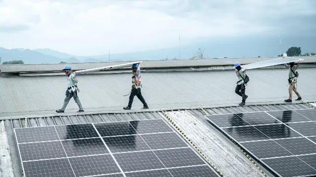 Teknisi berjalan di atap di antara panel surya